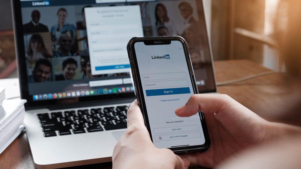 A women holds Apple iPhone X with LinkedIn application on the screen.