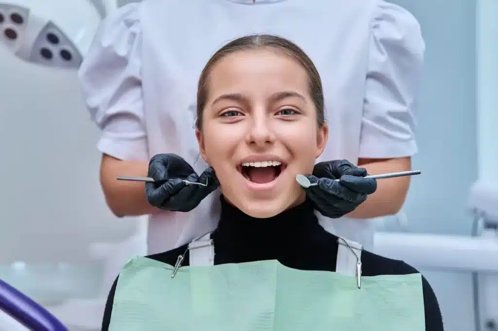 Teen patient smiling during a routine checkup at a Pediatric dentist Bradenton Florida office, with dental mirror and probe visible.