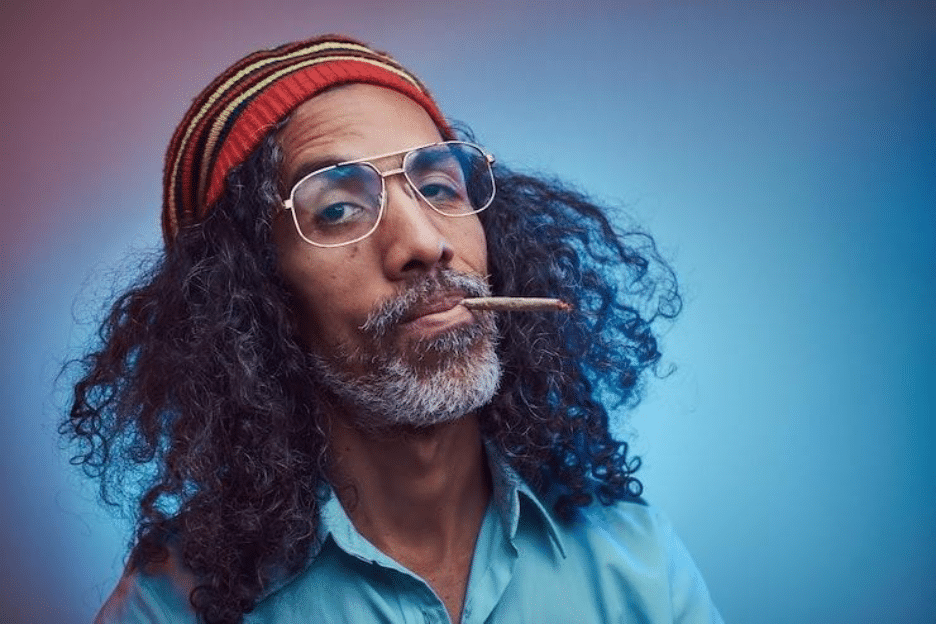 studio portrait of african rastafarian male smoking cigarettes. isolated on a blue background.