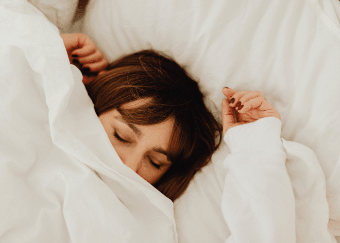 Woman Lying on Bed Covering Her Face With a White Duvet