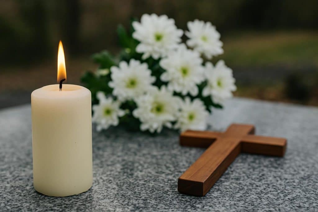 Candlelit memorial table with framed photos and flowers honoring loved ones at a family farewell