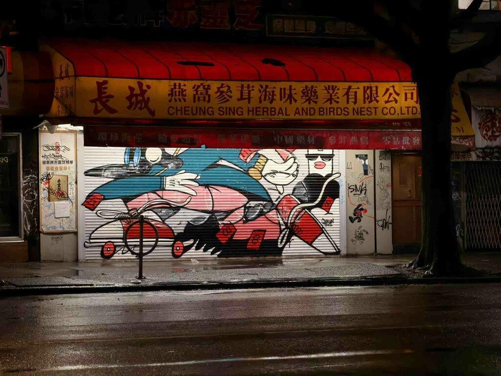 Chinatown Street Mural: Graffiti-style art on a closed storefront shutter under a red "Cheung Sing" herbal shop awning.
